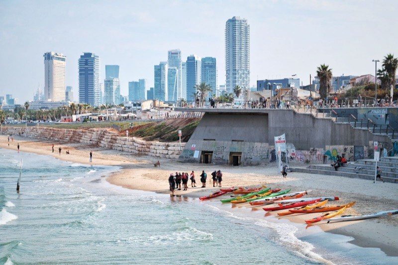 Sea kayaks on a Tel Aviv beach below the skyline