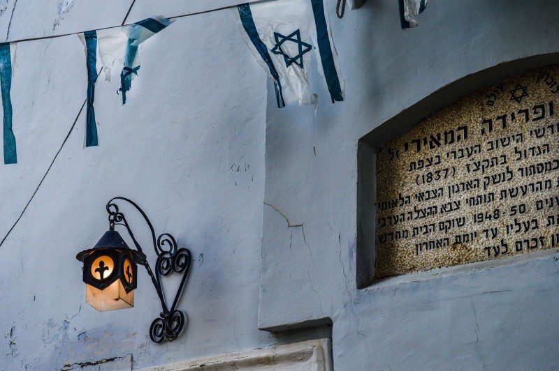 A lantern on the blue walls of Safed, with Israeli flags