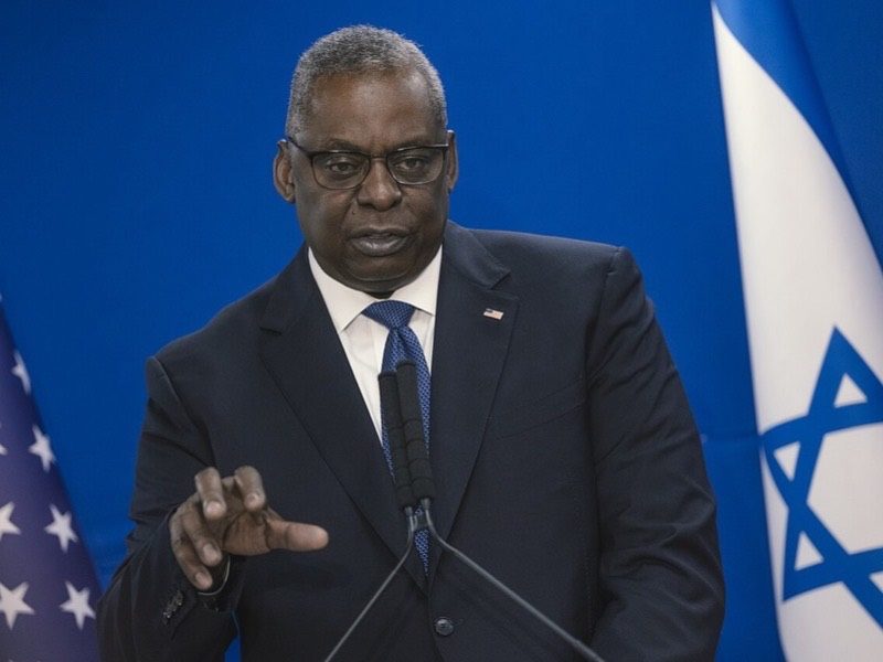 U.S. Secretary of Defense Lloyd Austin between the American and Israeli flags in Israel