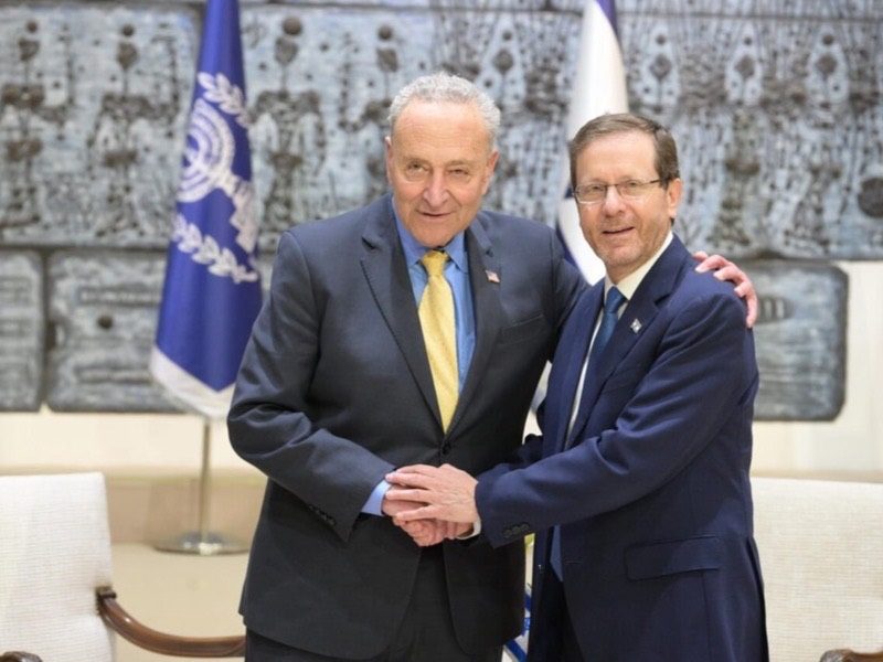 U.S. Senate Majority Leader Chuck Schumer clasping hands with Israeli President Isaac Herzog